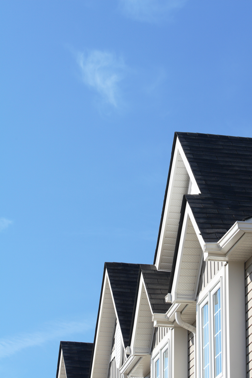 Row of roofs and eaves of homes with blue sky
