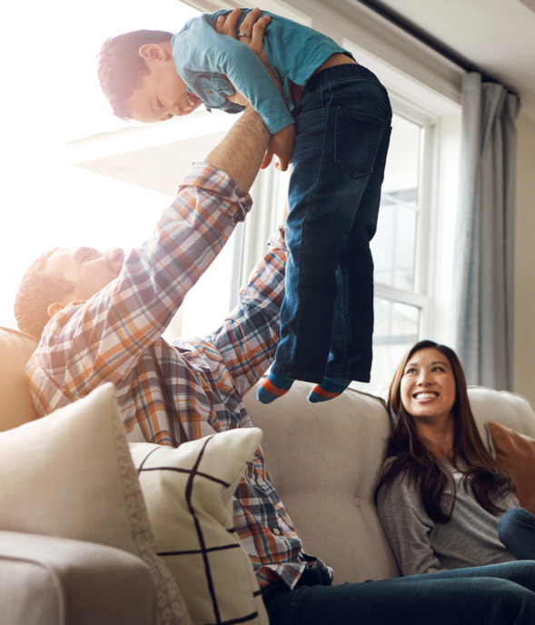 Family, dad and airplane with son on sofa for fun, childhood memory and together with love or playful support. Father, boy and bonding in living room in home with mom or sibling, affection and happy.